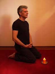 man meditating with candle