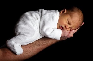 newborn sleeping on man's hand