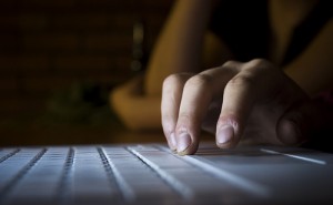 person typing on computer in dark
