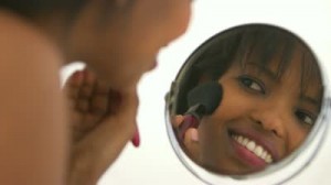 woman looking into make up mirror